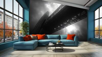 A dramatic black-and-white view of a towering bridge under clouds. Wall mural