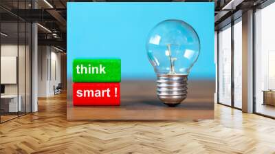 two blocks with the words think smart next to a free-standing antique light bulb against a blue background Wall mural