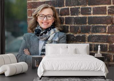 Portrait of a happy beautiful woman, 55 years old, smiling. On the street in the city, on the background of the old wall of red brick. Wall mural