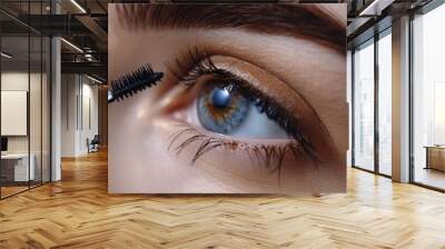 Close-up of a woman's blue eye with mascara being applied to her eyelashes. Wall mural