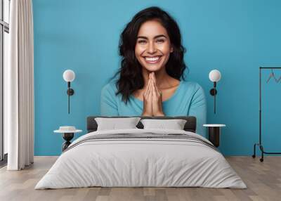 Hispanic woman standing in front of a blue background, showing a cheerful and caring smile. Romantic concept. Wall mural