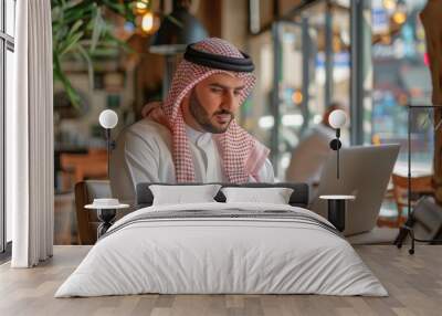 Arab man using laptop in cafe Wall mural