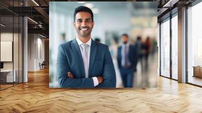 Portrait of a handsome smiling asian indian businessman boss in a suit standing in his modern business company office. his workers standing in the blurry background Wall mural