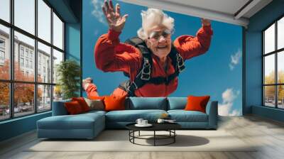 Portrait of happy senior woman jumping with skydiving in blue sky Wall mural