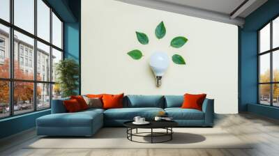 Energy saving lightbulb with green leaves background. Save energy concept, eco house and idea. Flat lay, top view Wall mural