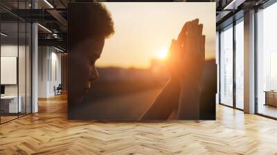 Hands of young christian woman praying at sunrise light, religion and spirituality concept Wall mural