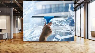 young female hand cleaning dirty glass window with a squeegee Wall mural