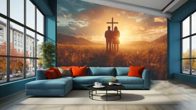 Couple praying together in a field in front of a cross at sunset Wall mural