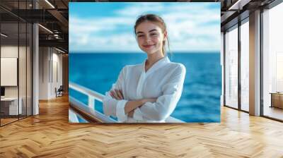 a young stewardess in a white blouse, standing by the railing on a cruise deck, the blue ocean and sky in the background, copy space to the left Wall mural