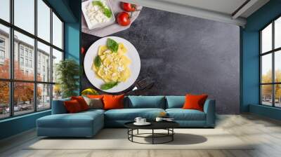 Boiled ravioli with basil, cheese and tomatoes on a black background Wall mural