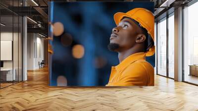 Engineer wearing protective helmet, gazing upwards, surrounded by soft bokeh lights for occupational safety concept Wall mural