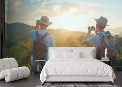 An Asian man and a young guy enjoy a summer holiday road trip together. The two young guys are looking at beautiful natural scenery of green countryside forest and mountains on a sunny day. Wall mural