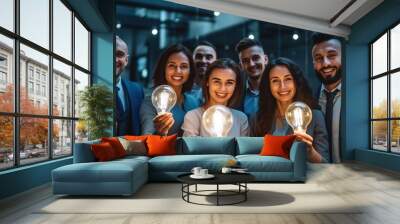 Happy creative team holding glowing lit light bulbs. Wall mural