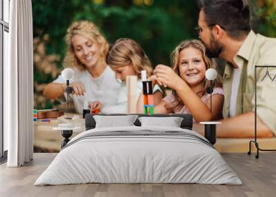 A cheerful family of four is sitting in nature and playing board game. Wall mural