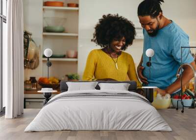 A happy multicultural couple is cooking dinner together at home. Wall mural