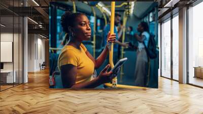 African american woman riding in a bus and using a smartphone during a night Wall mural