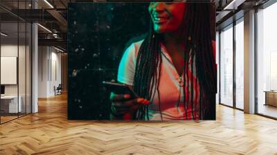 African american woman using smarthone while being illuminated by the green and red light Wall mural