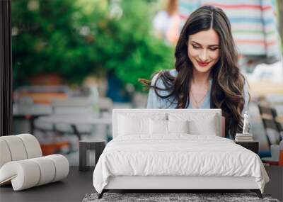 Beautiful woman sitting in a street cafe and using a laptop Wall mural