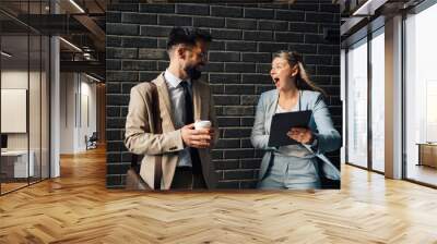 Businesspeople reacting to good news on tablet in office hallway Wall mural