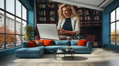 Businesswoman using a laptop for an online meeting while working in her office Wall mural