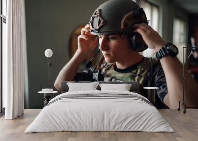 Close up of airsoft soldier in tactical vest putting helmet on head. Wall mural