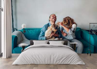 Couple petting their adopted dog while sitting on the couch at home Wall mural