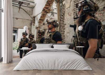 Group of brave soldiers with weapons at abandoned rustic building. Wall mural