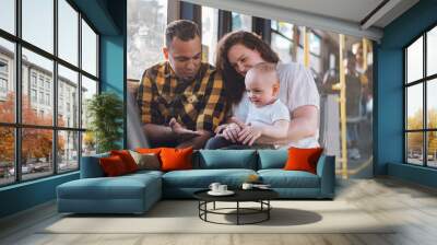 Happy parents and son riding in bus while baby sits in mother lap. Wall mural