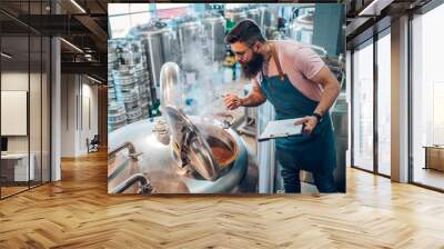 Man working in brewery and taking notes of the beer production Wall mural