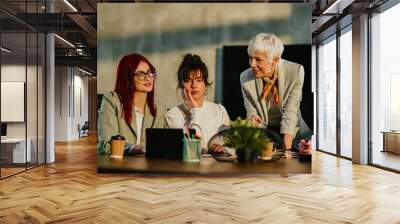 Mature manager tutoring and teaching her young staff at conference room Wall mural