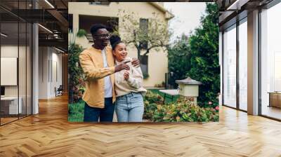 Multiracial couple holding keys and standing outside their new home Wall mural