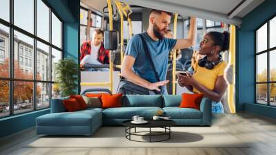 Multiracial friends talking and using a smartphone while riding a bus in the city Wall mural