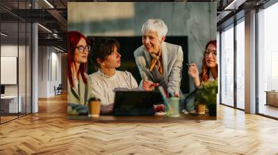 Old female manager teaching and coaching her young team at boardroom. Wall mural