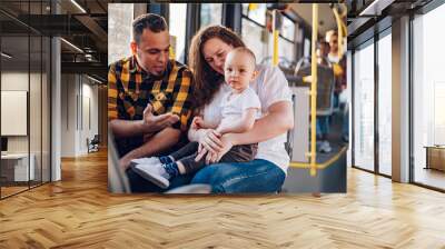 Parents riding a bus with their child during a day. Wall mural