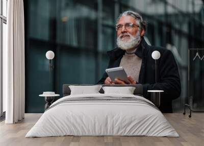 Portrait of a senior businessman using tablet outside of the office building Wall mural