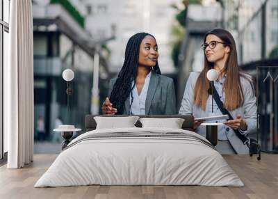 Two multiracial business woman meeting outside and using a tablet Wall mural