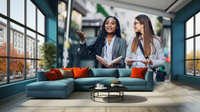 Two multiracial business woman meeting outside and using a tablet Wall mural