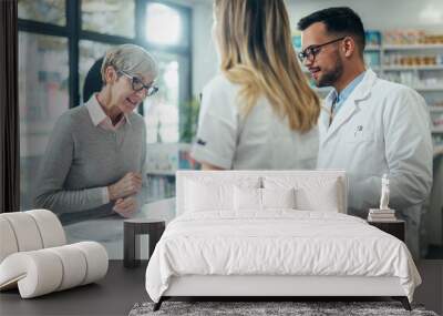 Two pharmacist giving prescription medications to senior female customer in a pharmacy Wall mural