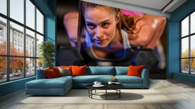 Woman in a sportswear training in a fitness gym doing pushups with dumbbells Wall mural