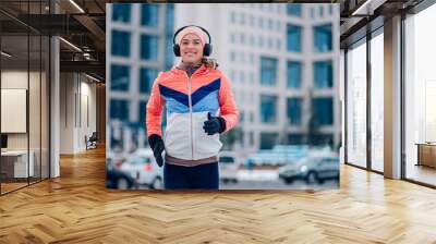 Woman running in the city on a cold winter day. Wall mural