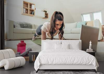 Woman training at home in a plank position Wall mural