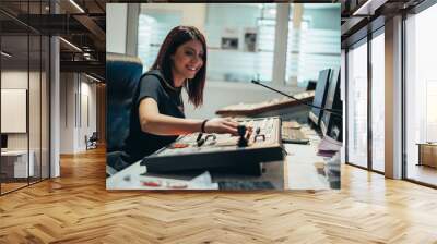 Young beautiful woman working in a broadcast control room on a tv station Wall mural