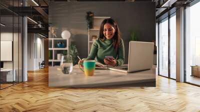 Young businesswoman working at home nd using laptop and smartphone Wall mural