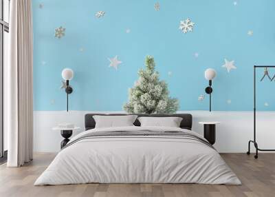 Creative layout with snowy Christmas tree, stars and snowflakes on bright blue background. Minimal winter nature holiday scene. Wall mural