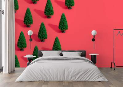 Minimal composition pattern background of green Christmas trees on pastel red. New Year concept. Wall mural