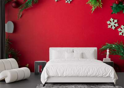 Red Christmas background with winter decoration, tree branches and leaves. Holiday copy space layout. Wall mural