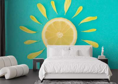 Sun made of lemon and yellow flower petals on bright blue background. Fruit summer minimal concept. Wall mural