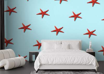 Trendy sunlight Summer pattern made with red starfish on bright light blue background. Minimal summer concept. Wall mural