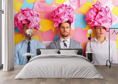 A lively group of four friends engages in a brainstorming session, each sporting a playful hat made of crumpled pink paper. They are surrounded by multicolored sticky notes that spark inspiration Wall mural