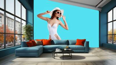 attractive girl in a white bikini, hat, sunglasses, emotionally opened mouth on a bright blue backgr Wall mural